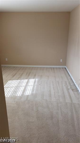 empty room featuring baseboards and light colored carpet