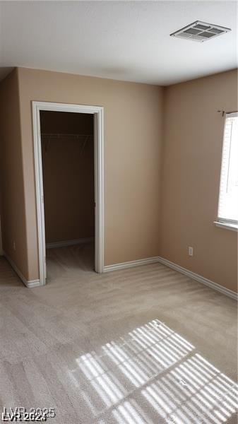 empty room featuring light colored carpet, visible vents, and baseboards