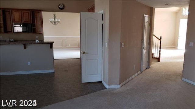 kitchen featuring black microwave, a breakfast bar, brown cabinets, open shelves, and dark countertops