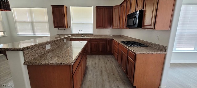 4798 Luna Ridge Ct, Las Vegas, NV 89129 - kitchen featuring light wood finished floors, a sink, gas cooktop, black microwave, and light stone counters