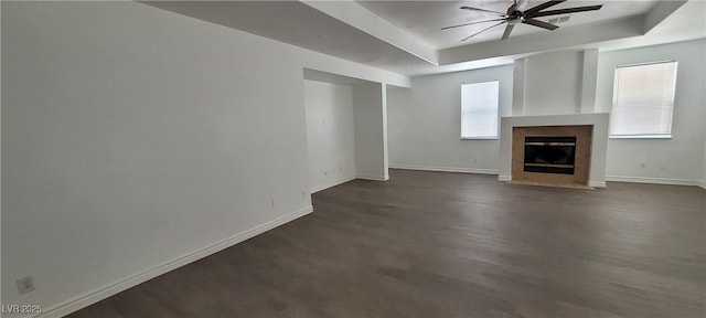 4798 Luna Ridge Ct, Las Vegas, NV 89129 - unfurnished living room featuring a tray ceiling, ceiling fan, baseboards, a fireplace with flush hearth, and dark wood-style floors