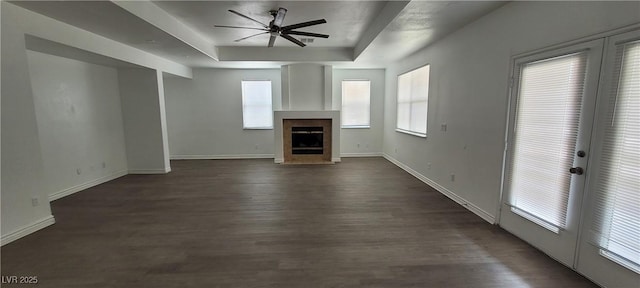 4798 Luna Ridge Ct, Las Vegas, NV 89129 - unfurnished living room featuring a ceiling fan, a tray ceiling, healthy amount of natural light, and dark wood-style flooring