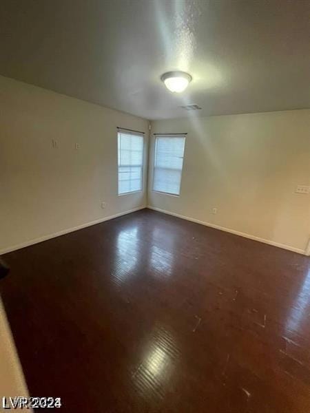 empty room with dark wood-type flooring and baseboards