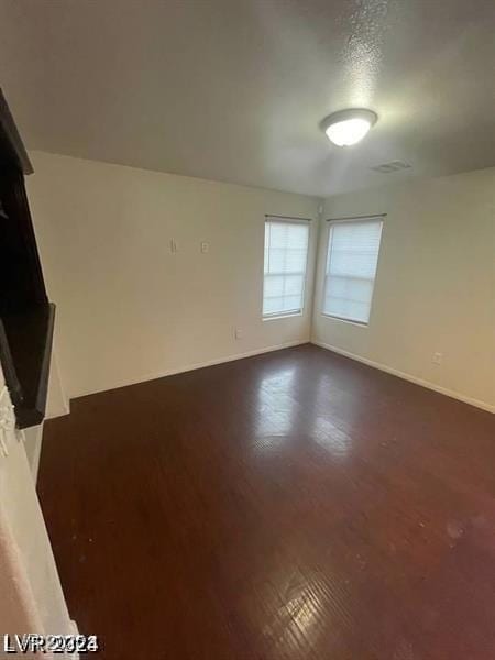 empty room with dark wood-style floors and baseboards