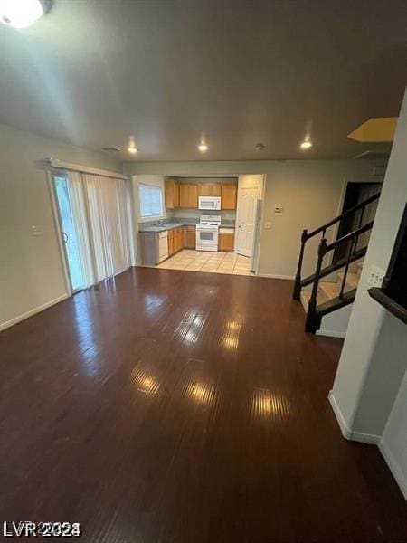 unfurnished living room featuring light wood-style flooring, stairs, baseboards, and recessed lighting