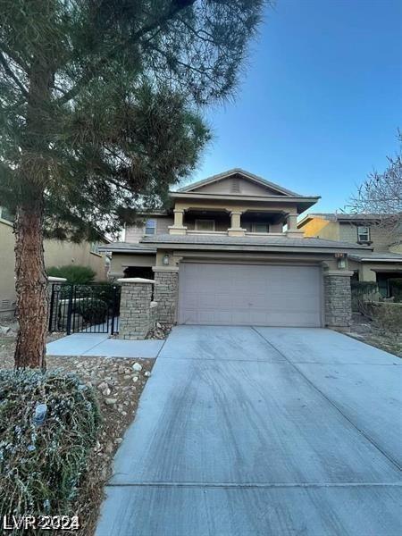 view of front facade featuring stone siding, concrete driveway, and fence