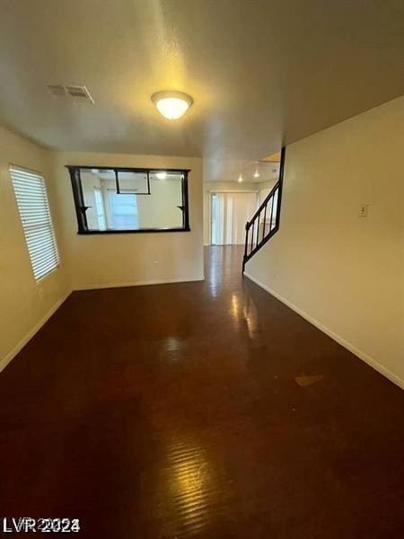 unfurnished room with visible vents, stairway, and baseboards