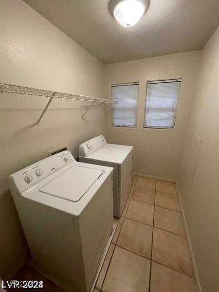 washroom with laundry area, independent washer and dryer, light tile patterned flooring, and baseboards