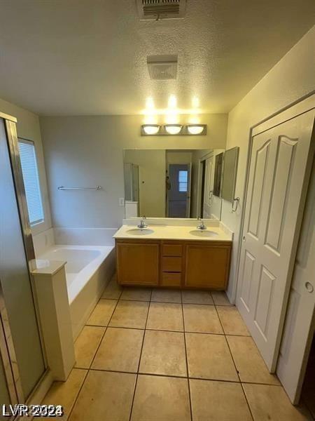 bathroom featuring a sink, visible vents, a bath, tile patterned floors, and double vanity