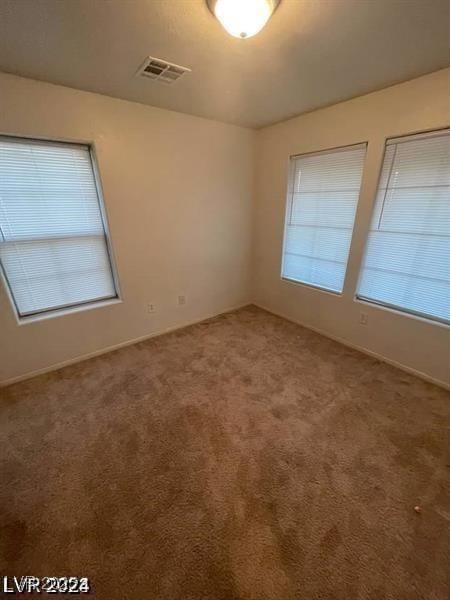 carpeted spare room featuring visible vents