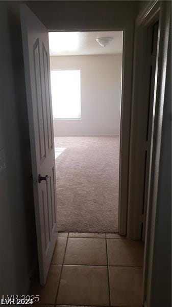 hall with light tile patterned flooring and light colored carpet