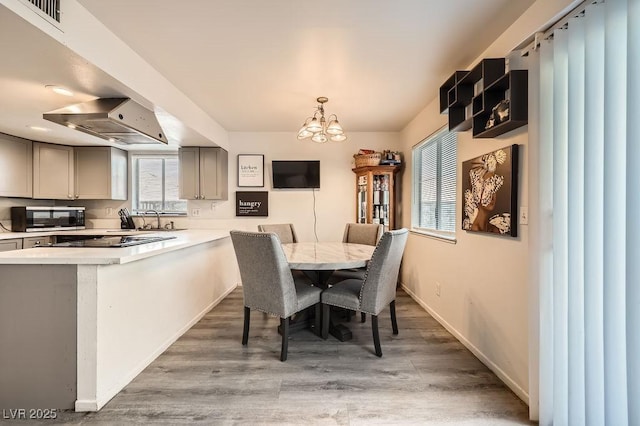 dining area featuring visible vents, a notable chandelier, baseboards, and wood finished floors