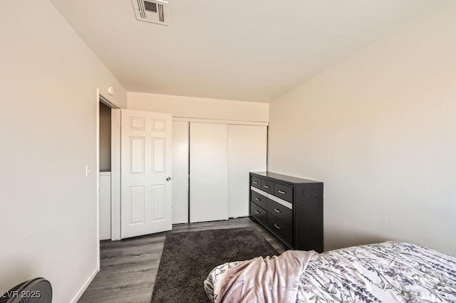 bedroom with dark wood-type flooring, a closet, and visible vents