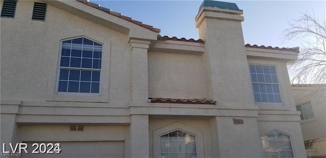 view of side of property with a tile roof, a chimney, and stucco siding