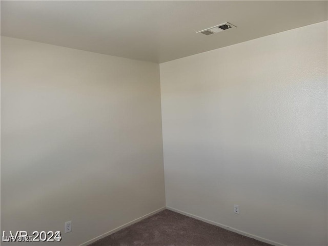 spare room with baseboards, visible vents, and dark colored carpet