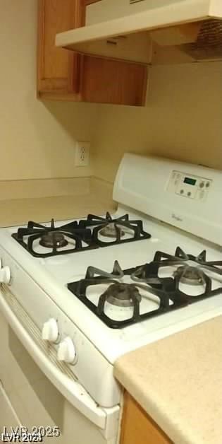 kitchen with brown cabinetry, light countertops, and white gas stove