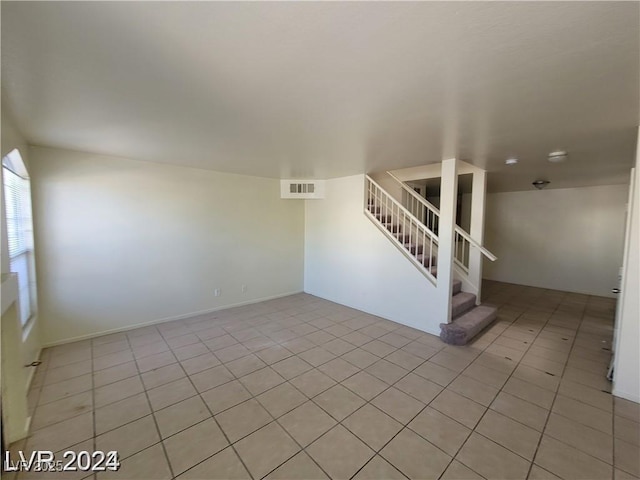 empty room featuring light tile patterned floors, stairs, and visible vents