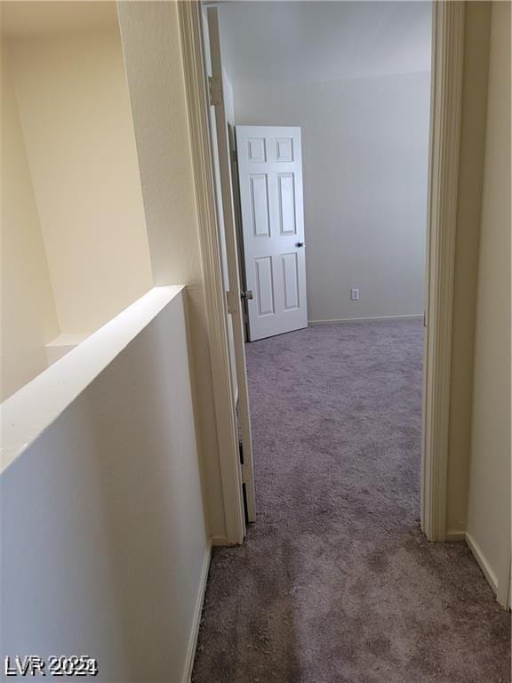 hallway featuring carpet and baseboards