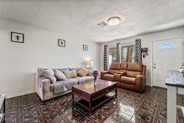 living room featuring visible vents, a textured ceiling, and baseboards