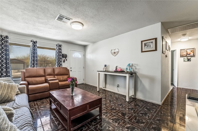 living room featuring baseboards, visible vents, and a textured ceiling