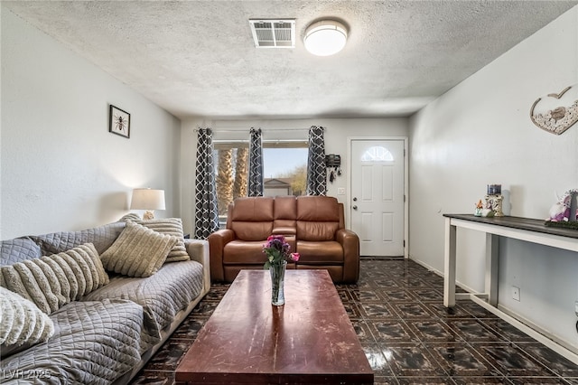 living area with baseboards, dark floors, visible vents, and a textured ceiling