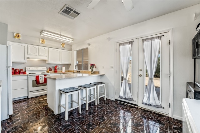 kitchen featuring visible vents, french doors, a peninsula, white appliances, and white cabinetry