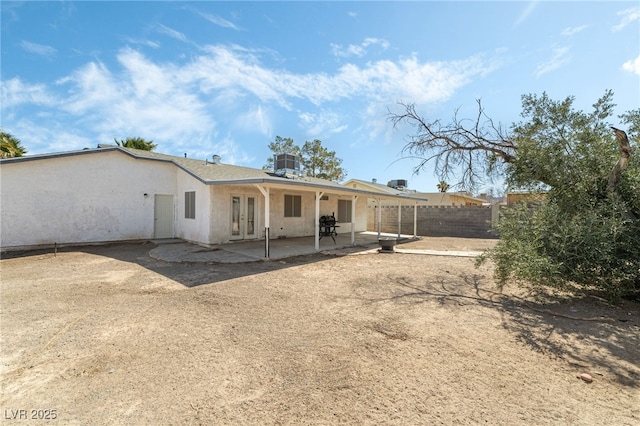 back of property with stucco siding, a patio, central AC, fence, and french doors