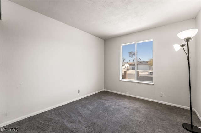 unfurnished room with baseboards and dark colored carpet