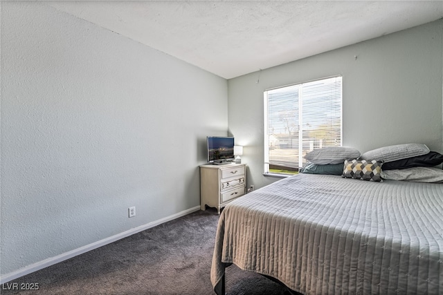 bedroom with a textured wall, baseboards, and dark carpet