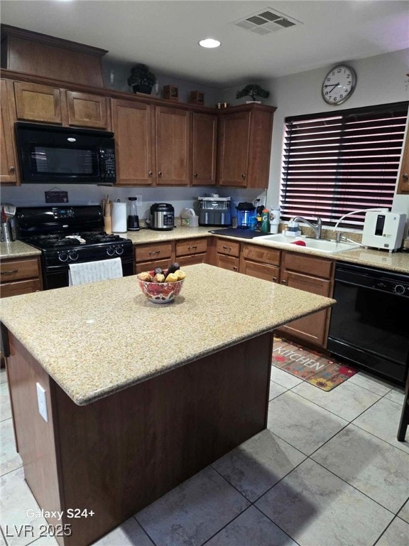 kitchen with black appliances, visible vents, a sink, and a center island