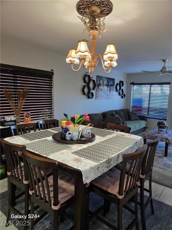 tiled dining area featuring ceiling fan with notable chandelier