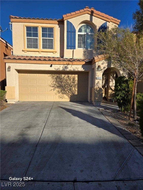 view of front facade with a garage, driveway, a tile roof, and stucco siding