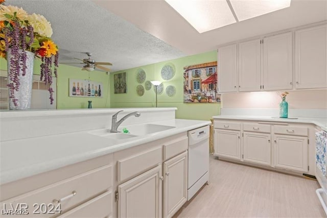 kitchen featuring white cabinets, light countertops, white dishwasher, and a sink