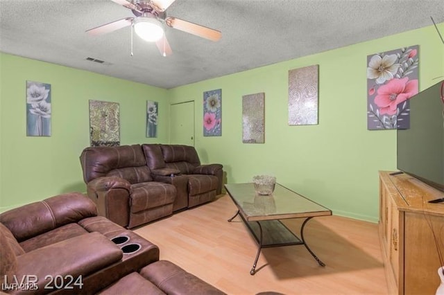 living room with a ceiling fan, visible vents, a textured ceiling, and wood finished floors