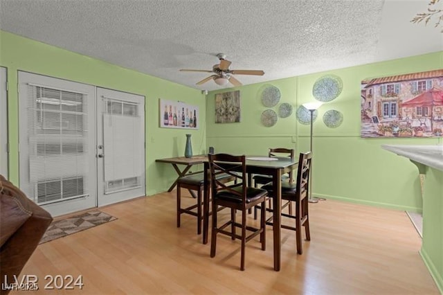 dining area with light wood-style floors, ceiling fan, and a textured ceiling