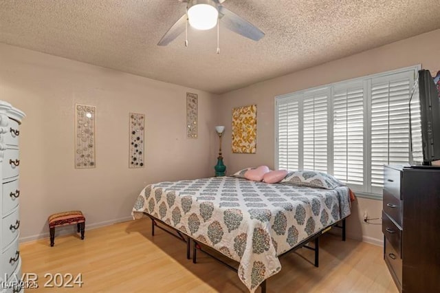 bedroom featuring a textured ceiling, ceiling fan, light wood finished floors, and baseboards