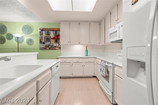 kitchen with white cabinets, white appliances, light wood-type flooring, and light countertops