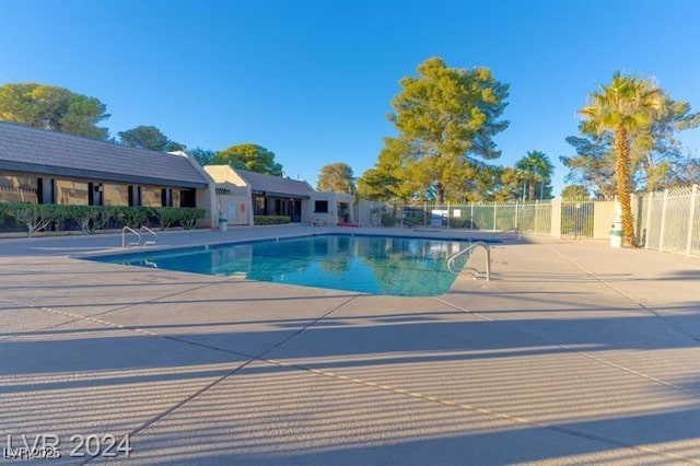 community pool with a patio area and fence