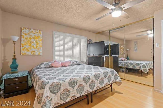 bedroom with a textured ceiling, a closet, wood finished floors, and a ceiling fan