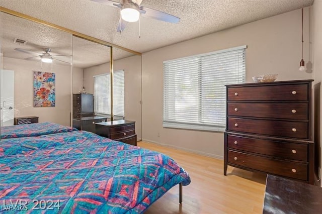 bedroom featuring light wood-style floors, a closet, visible vents, and a textured ceiling