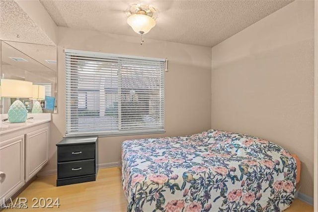 bedroom featuring a textured ceiling and light wood finished floors