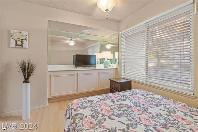 bedroom featuring light wood-type flooring, a textured ceiling, and baseboards