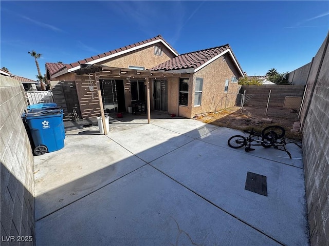 back of house featuring a patio area, a fenced backyard, stucco siding, and a tiled roof