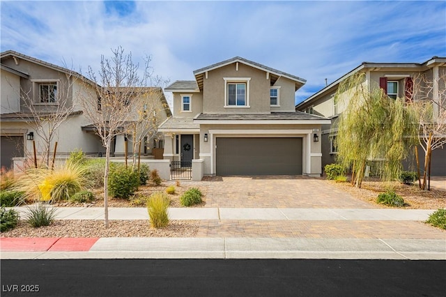 view of front facade featuring an attached garage, fence, decorative driveway, and stucco siding