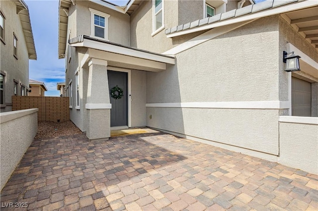 doorway to property featuring fence and stucco siding