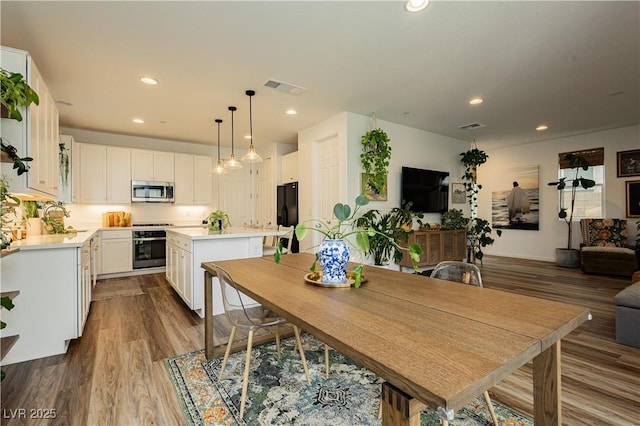 dining space featuring dark wood finished floors, visible vents, and recessed lighting