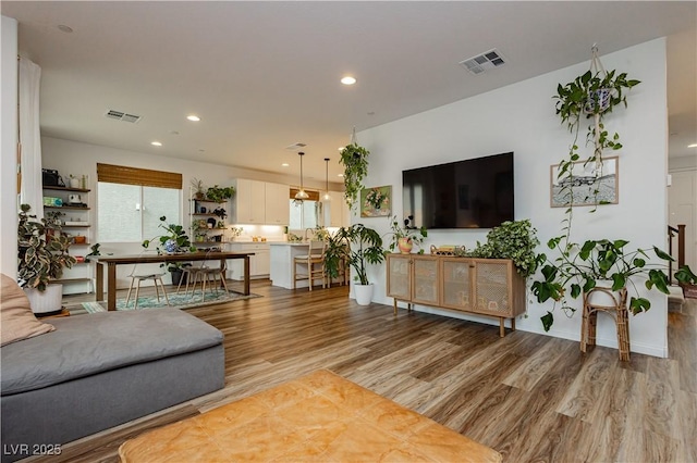 living room featuring light wood-type flooring, visible vents, and recessed lighting