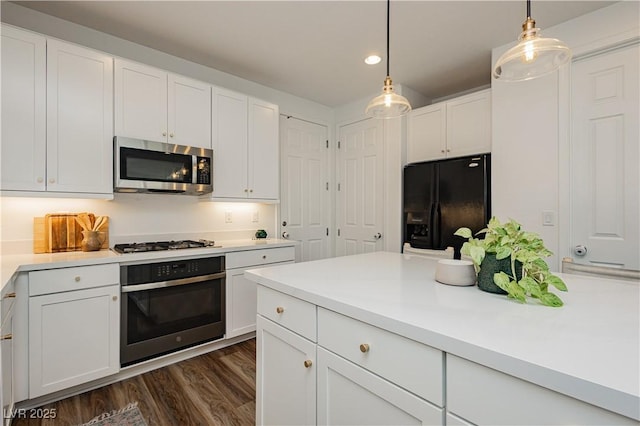 kitchen featuring dark wood-style floors, pendant lighting, light countertops, appliances with stainless steel finishes, and white cabinets