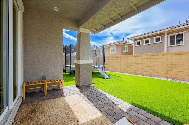 view of patio featuring a trampoline and a fenced backyard