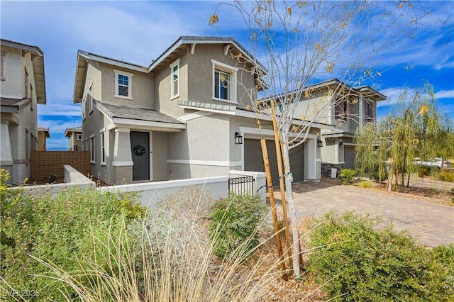 view of front facade with an attached garage, fence private yard, decorative driveway, and stucco siding